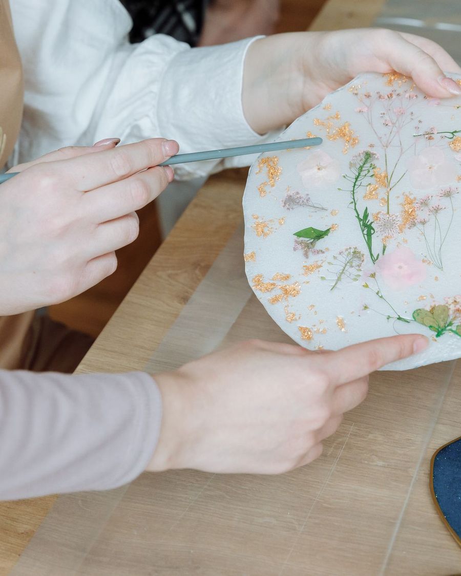 Mani che rifiniscono un oggetto in resina con fiori essiccati