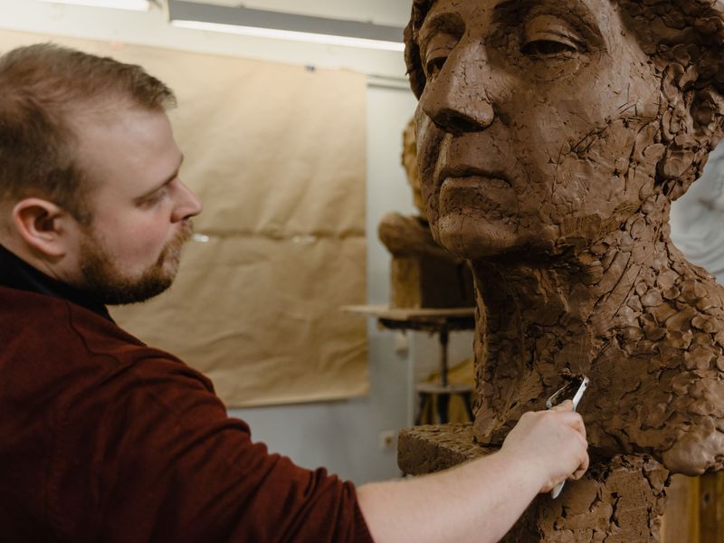 Scultore che modella una testa in argilla
