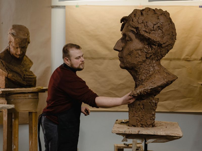 Scultore al lavoro su un busto in argilla nello studio