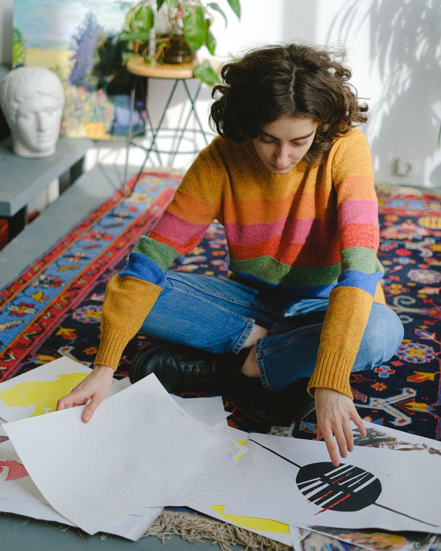 Una donna crea con carta e colori seduta su un tappeto